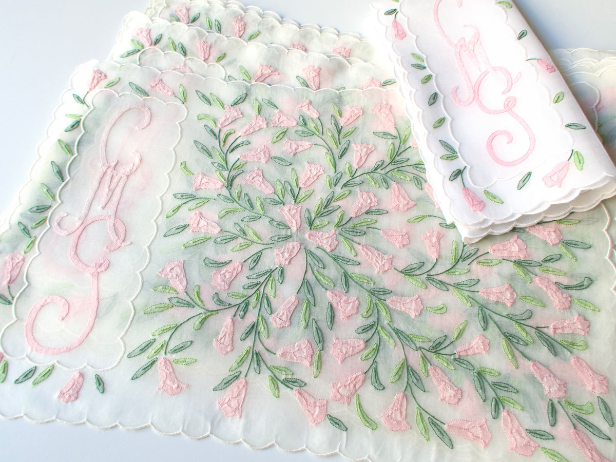 Madeira embroidered organdy placemats fanned to show pink flower embroidery and cursive triple monogram
