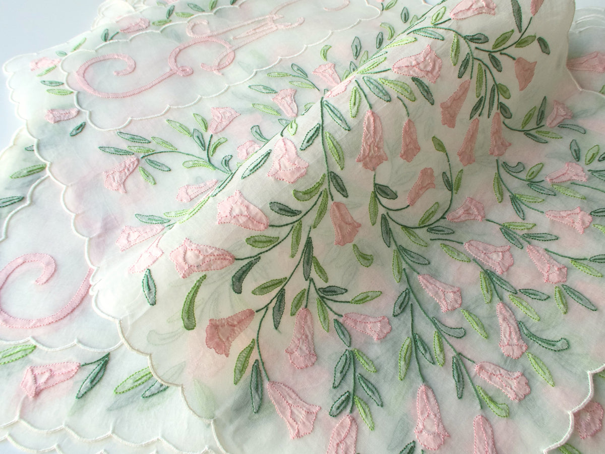 Draped Madeira organdy placemat showing cascade of pink shadow work flowers and trailing green stems​​​​​​​​​​​​​​​​