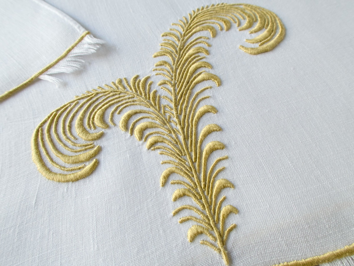Marghab linen towels in the “Plume” pattern, hand embroidered in gold with feather motifs and eyelash fringe.