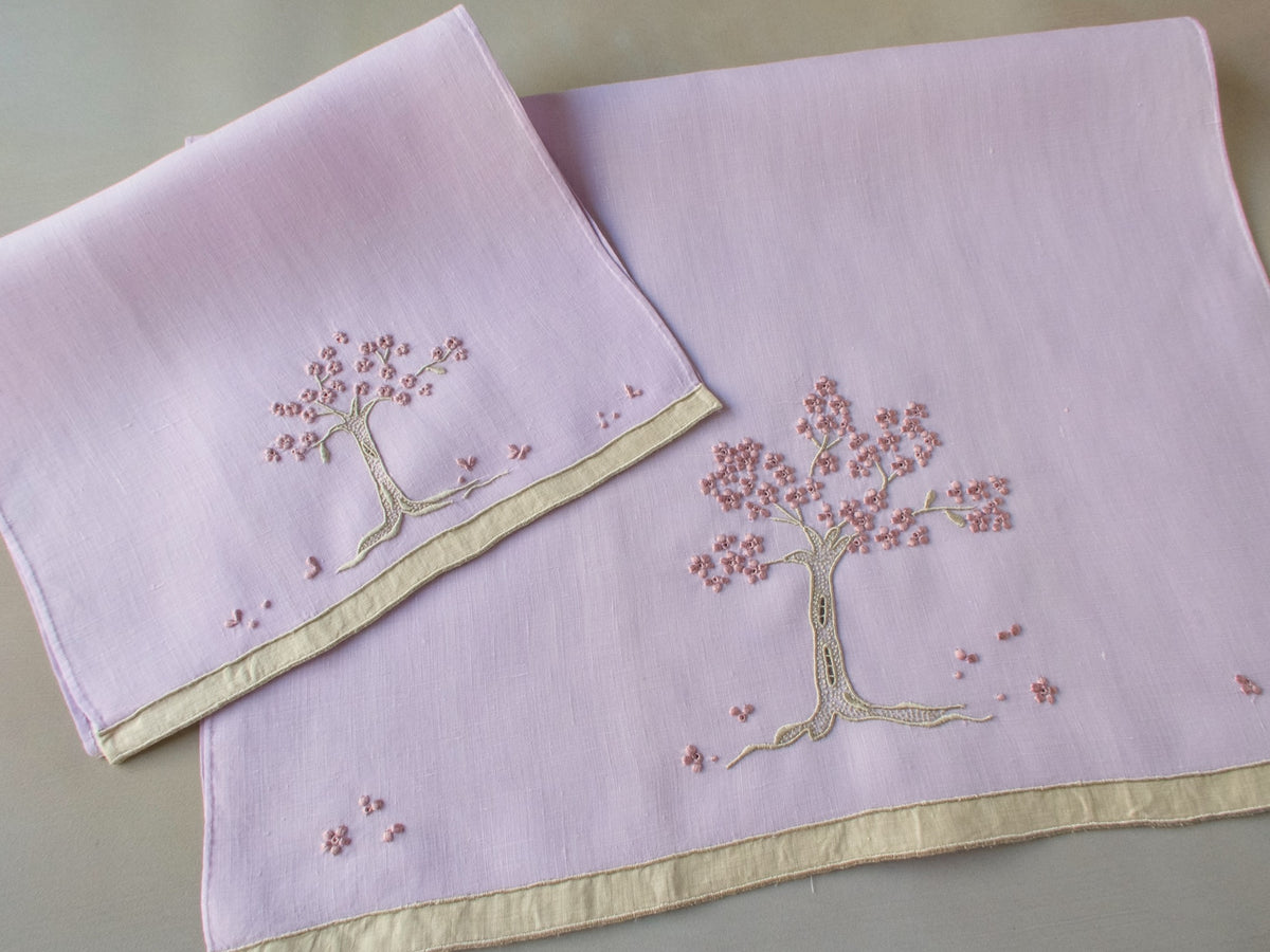 Marghab linen towels in the “Jacaranda Tree” pattern, featuring an embroidered jacaranda tree in bloom — guest and fingertip sizes shown together.