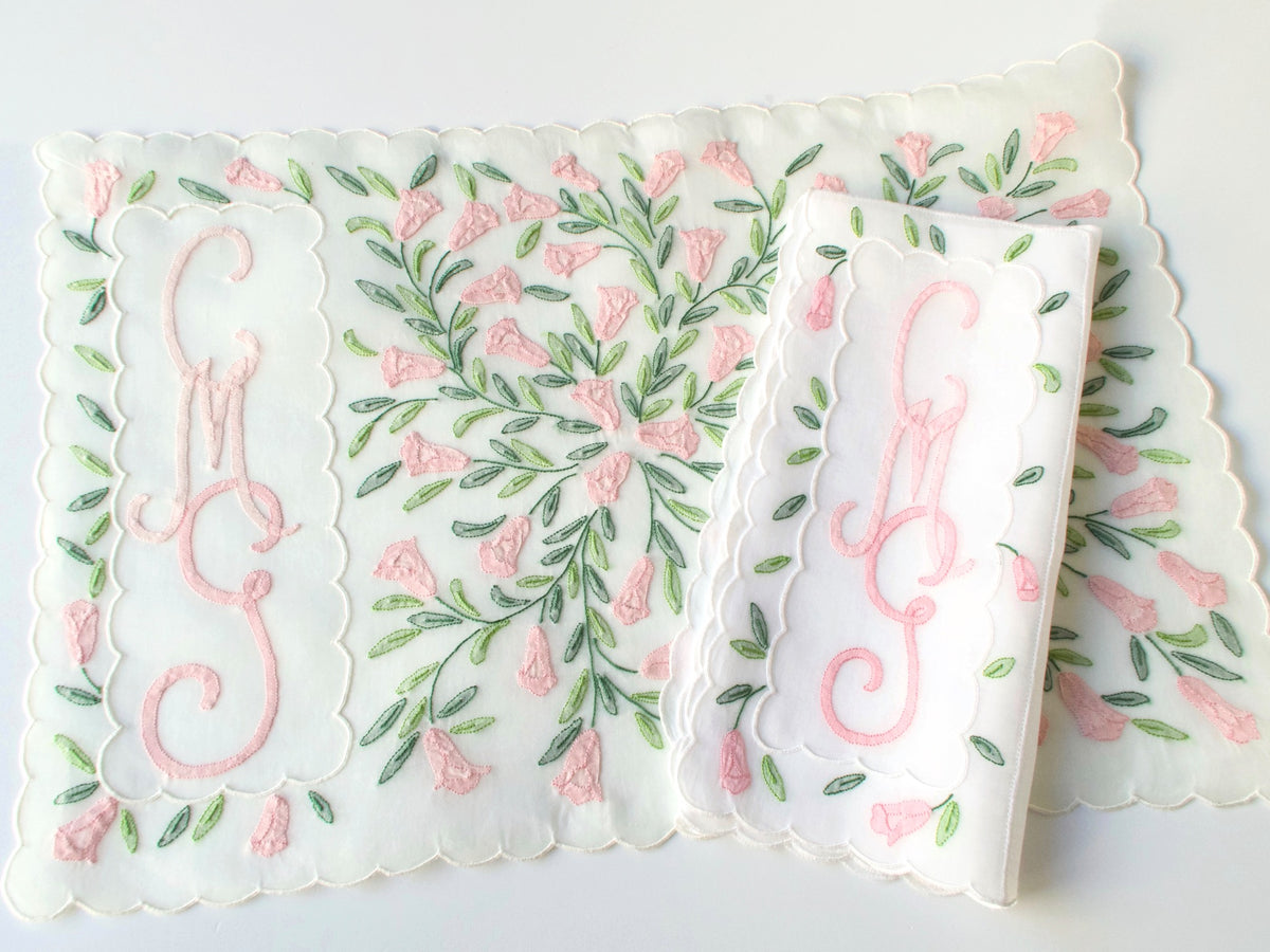Overhead view of Madeira organdy placemat showing full pink floral shadow work pattern and triple monogram at center