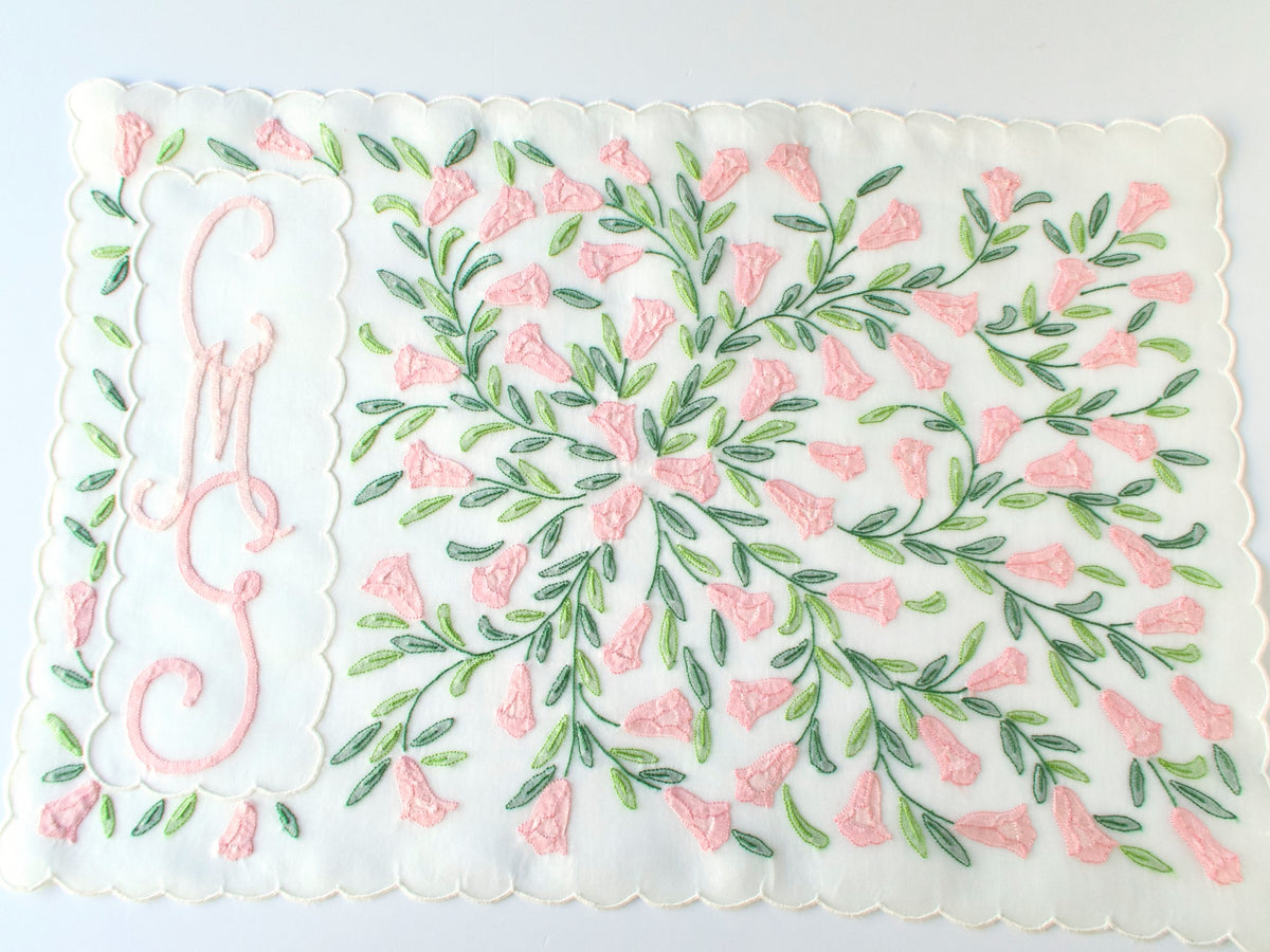 Detail of center medallion on Madeira organdy placemat with dense pink shadow work florals and green leaf stems