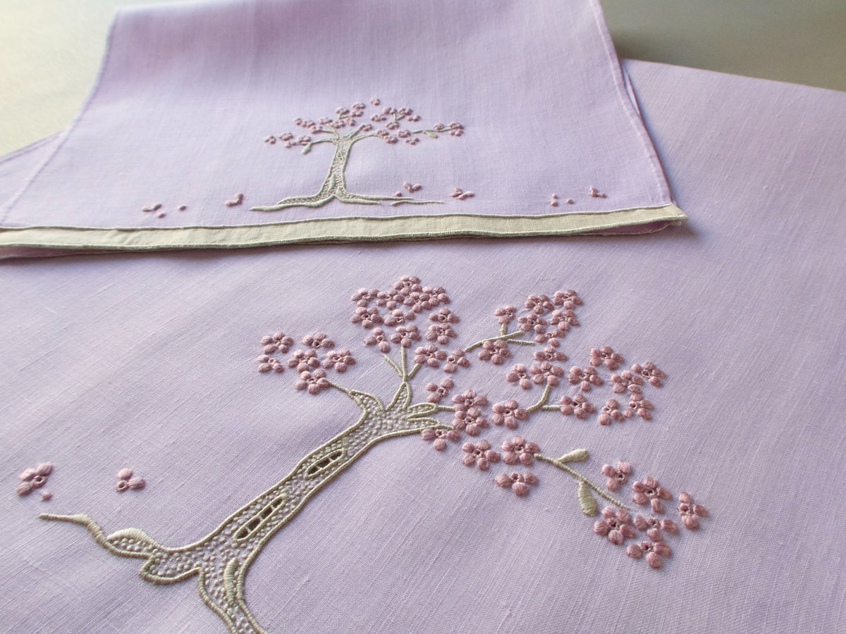Marghab linen towels in the “Jacaranda Tree” pattern, featuring an embroidered jacaranda tree in bloom — guest and fingertip sizes shown together.