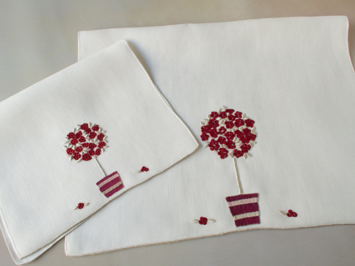Marghab linen towels in the “Rose Tree” pattern, featuring a potted rose tree with maroon embroidered blossoms in a seldom-seen color — guest and fingertip sizes shown together.