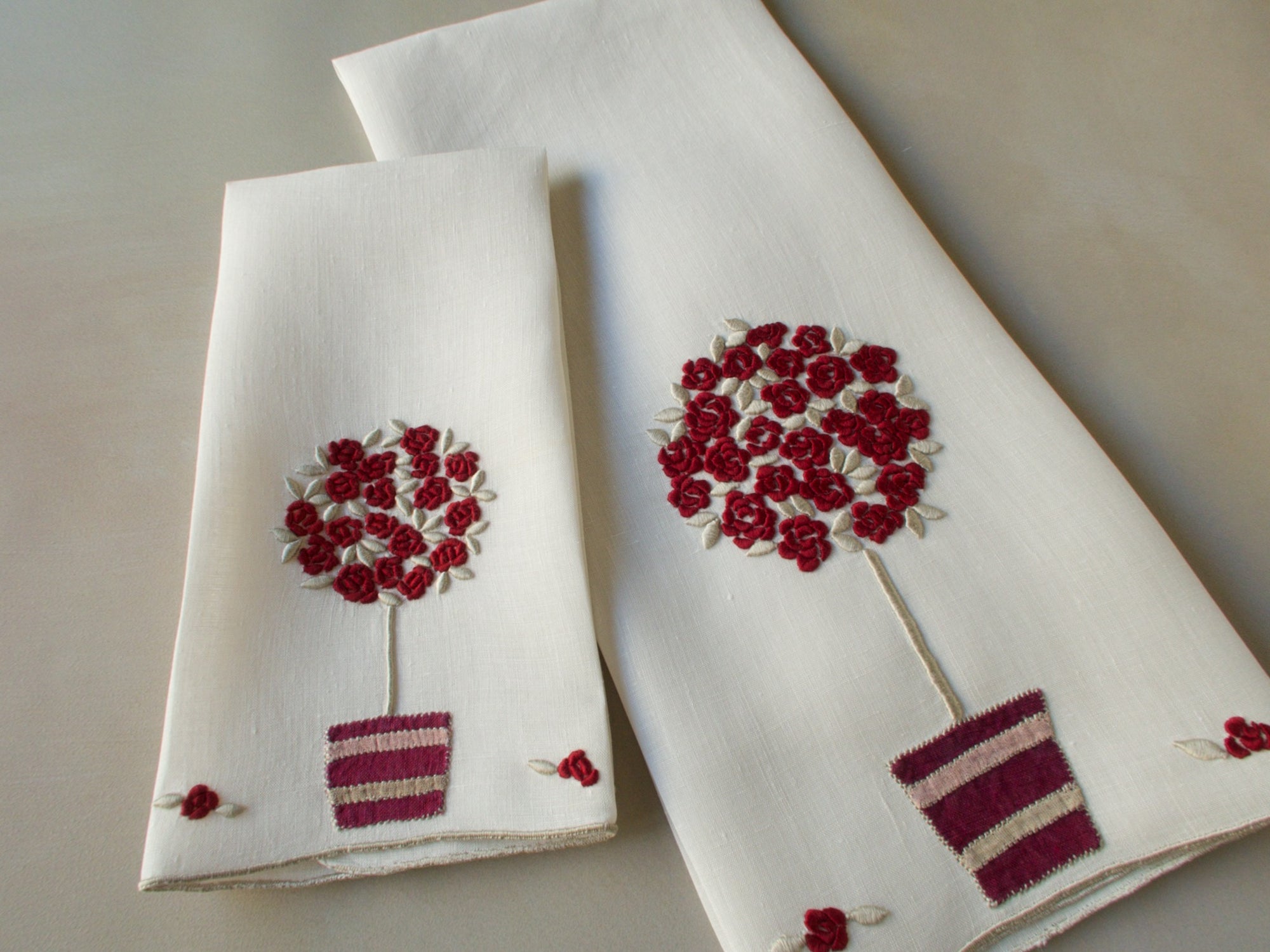 Marghab linen towels in the “Rose Tree” pattern, featuring a potted rose tree with maroon embroidered blossoms in a seldom-seen color — guest and fingertip sizes shown together.