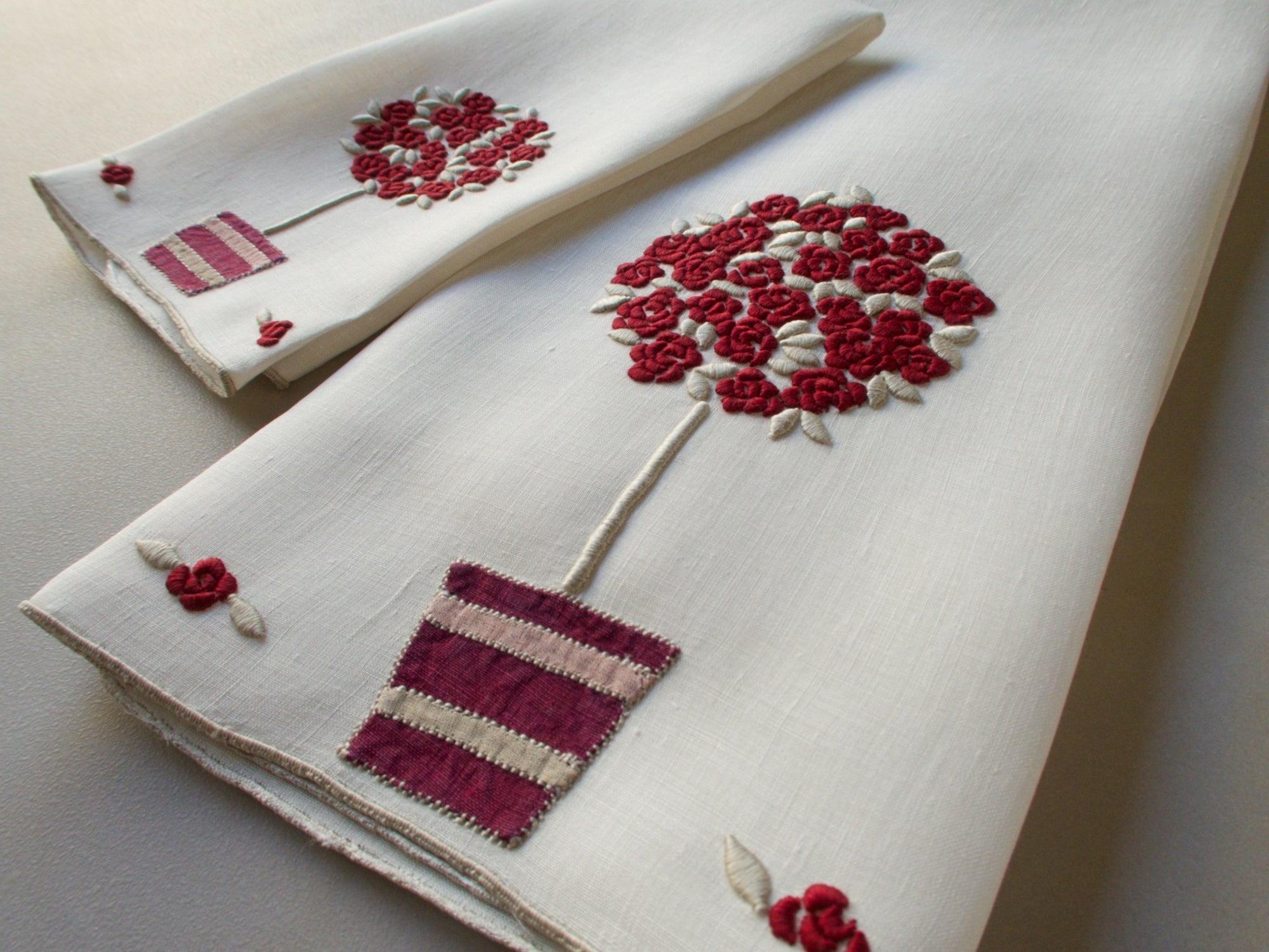 Marghab linen towels in the “Rose Tree” pattern, featuring a potted rose tree with maroon embroidered blossoms in a seldom-seen color — guest and fingertip sizes shown together.