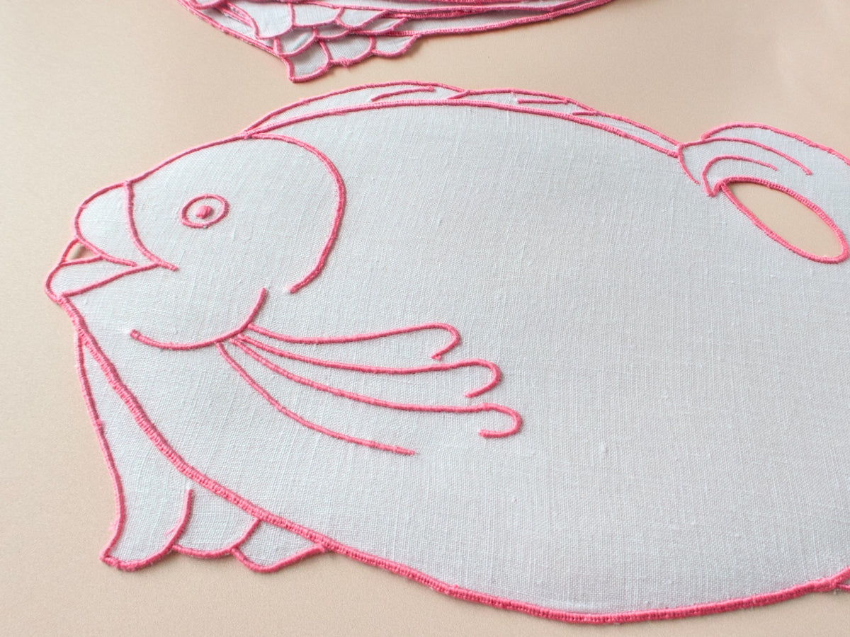 Fish-shaped white linen cocktail napkin outlined in fuchsia embroidery, hand embroidered in Madeira