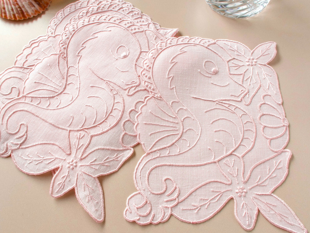 Detail of pink Madeira linen cocktail napkin showing hand embroidered floral cutwork and scalloped edges