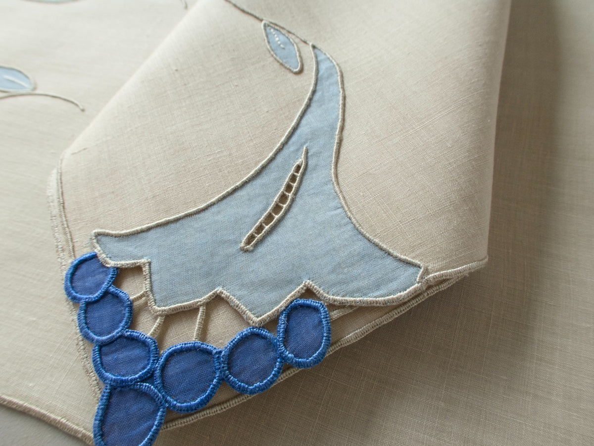 Vintage Marghab “Trumpet Flower” placemat and napkin set with matching table runner, hand embroidered in Madeira in layered blue organdy appliqué with raised trumpet blossom motifs and cutwork detailing.