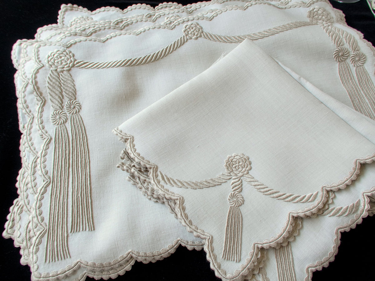 Stacked set of vintage Marghab “Cord &amp; Tassel” placemats and napkins, hand embroidered in Madeira on fine linen with intricate raised cord and tassel motifs in dimensional relief.
