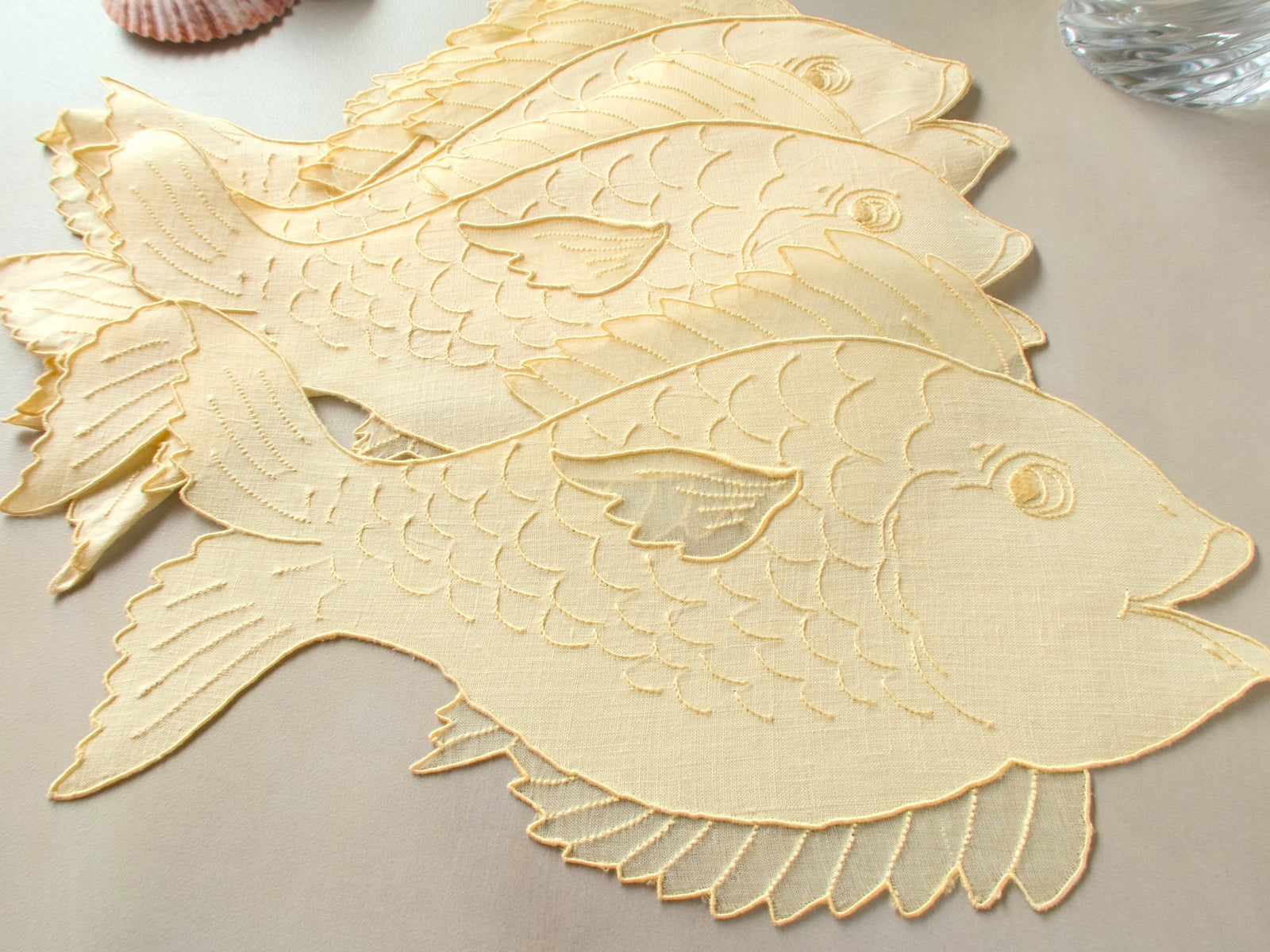 Set of fish-shaped vintage Madeira cocktail napkins in Irish linen and organdy showing layered embroidered scales and delicate fins​​​​​​​​​​​​​​​​