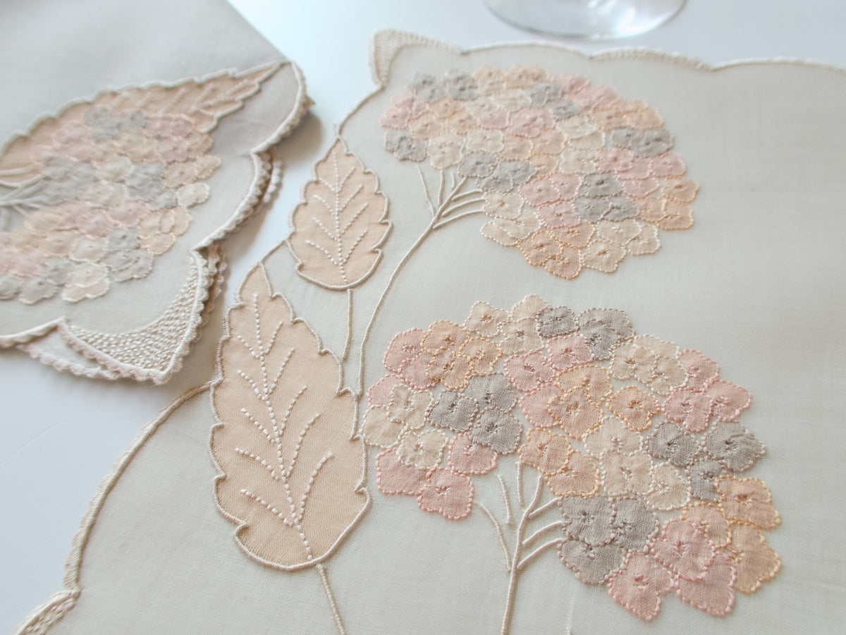 Vintage Marghab “Hydrangea” placemat and napkin set, hand embroidered in Madeira on fine organdy and linen, featuring intricate hydrangea blossoms in soft shades of cream and beige.