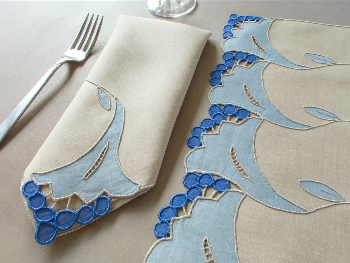 Vintage Marghab “Trumpet Flower” placemat and napkin set with matching table runner, hand embroidered in Madeira in layered blue organdy appliqué with raised trumpet blossom motifs and cutwork detailing.