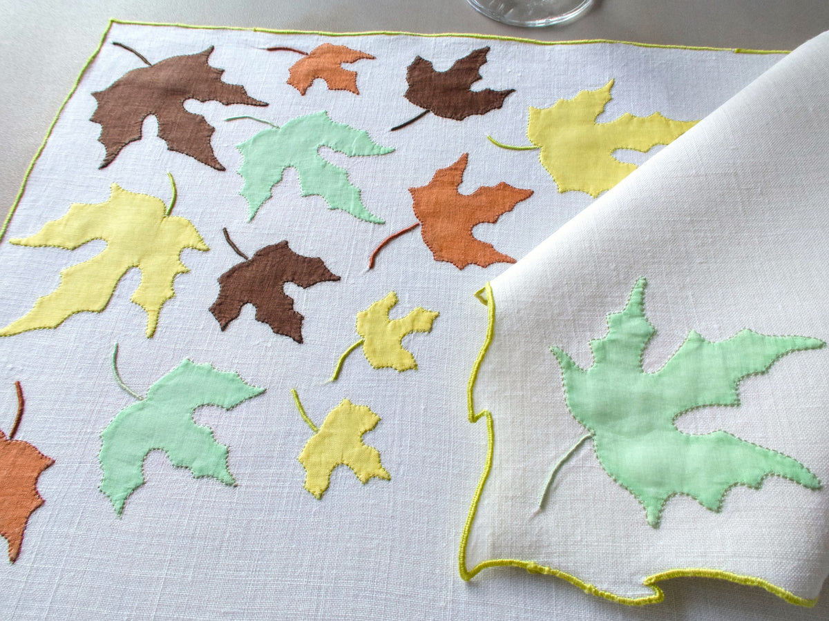Vintage Marghab “Autumn Leaves” placemat and napkin set, hand embroidered in Madeira on fine linen with appliquéd fall leaves in rich tones edged in chartreuse embroidery.