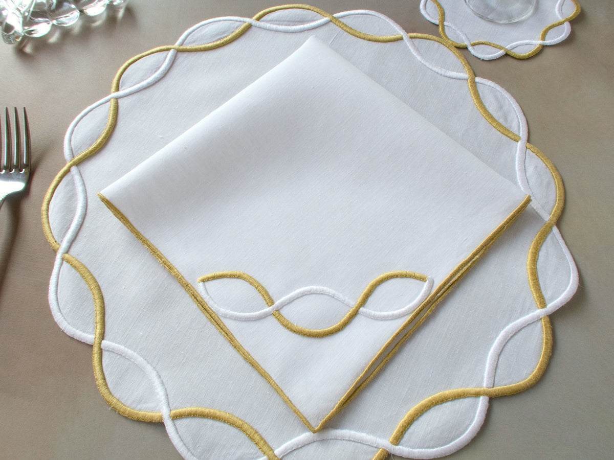 Vintage Marghab “Andante” linen placemat and napkin set, hand embroidered in gold and white on fine linen, featuring a signature looping motif.
