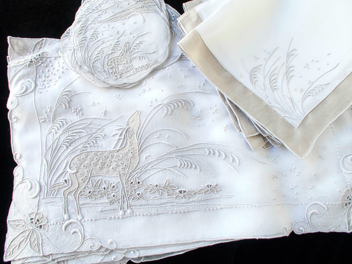 Vintage Marghab "Deer" placemat set with embroidered placemat, coasters and bordered napkins on a black background