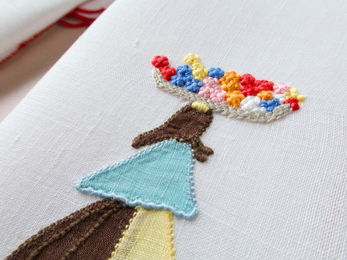 Close-up detail of vintage Marghab Flower Woman cocktail napkin showing colorful French knot embroidery in flower basket on white linen