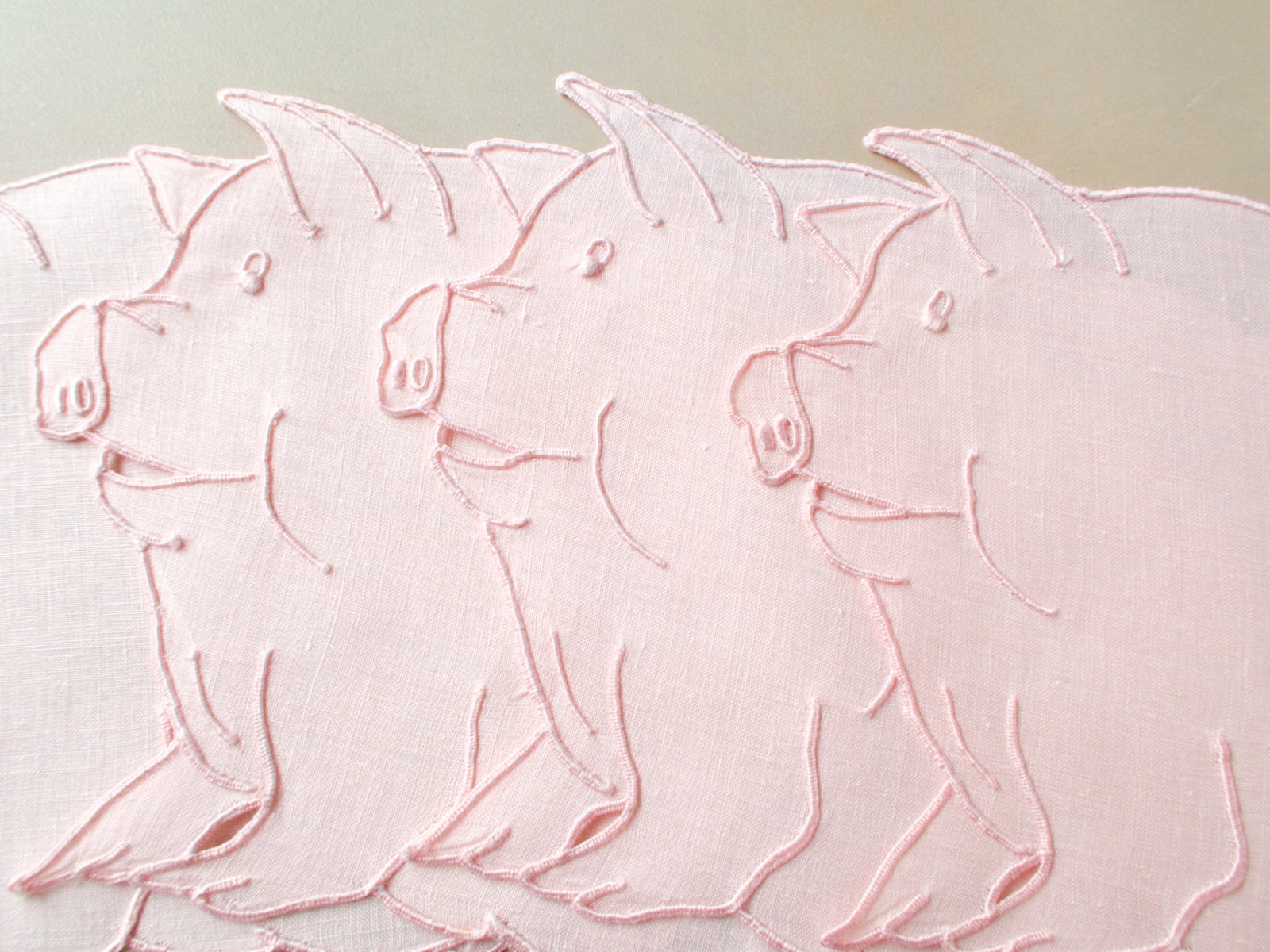 Pink pig-shaped vintage Madeira cocktail napkins on Irish linen, set of eight, showing expressive embroidered faces and shaped edges.