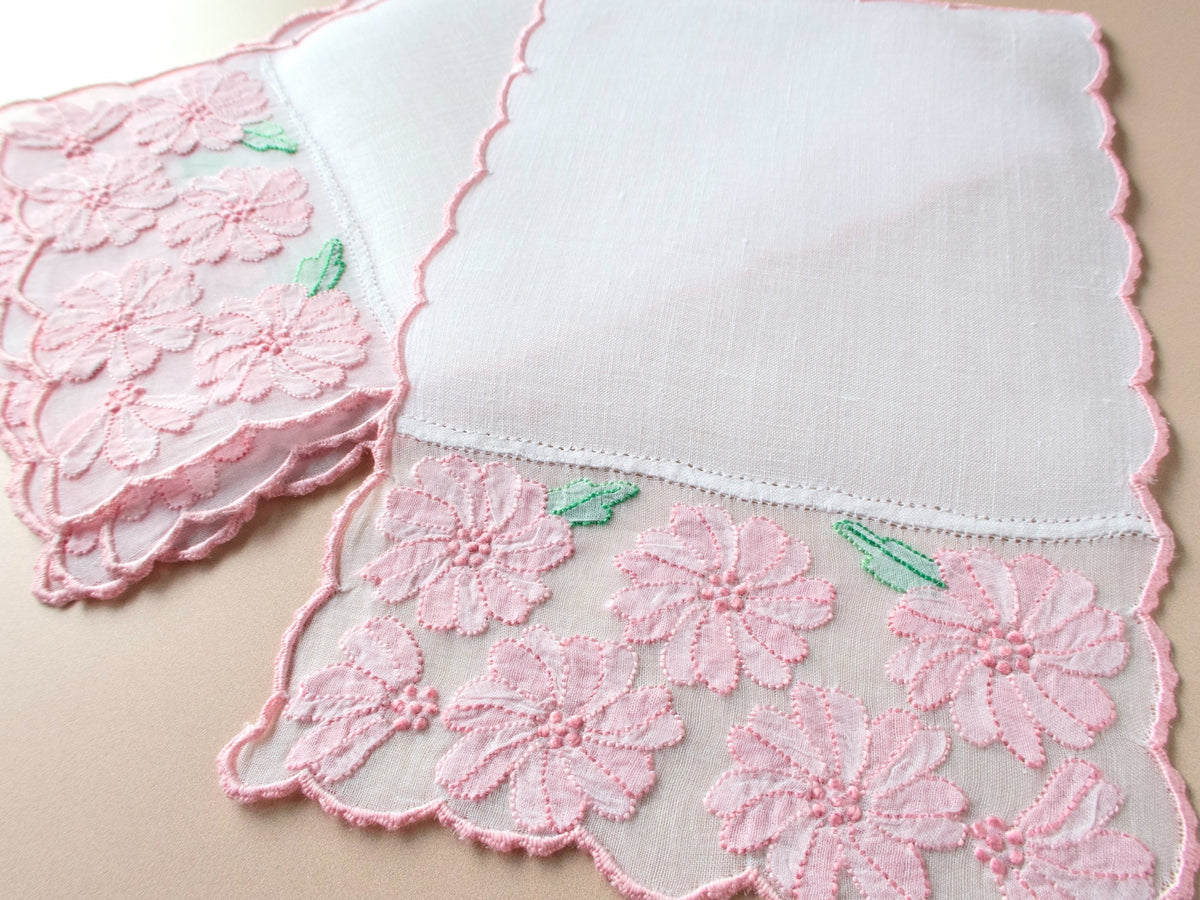 Close-up of vintage Madeira cocktail napkin showing pink shadow work flowers on sheer organdy inset and delicate scalloped pink edge.​​​​​​​​​​​​​​​​