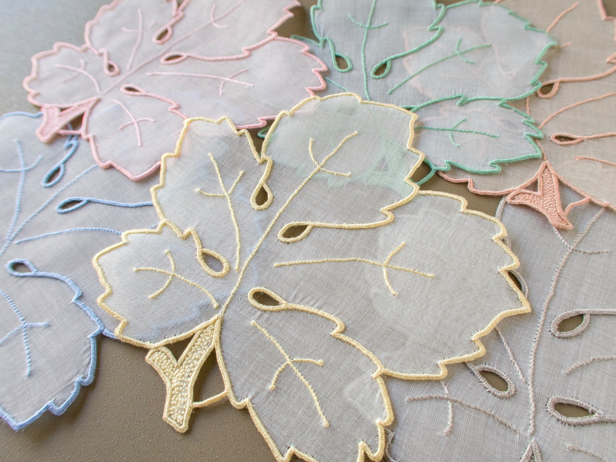 Close view of vintage Madeira organdy cocktail napkin shaped like a leaf with embroidered veins and stem