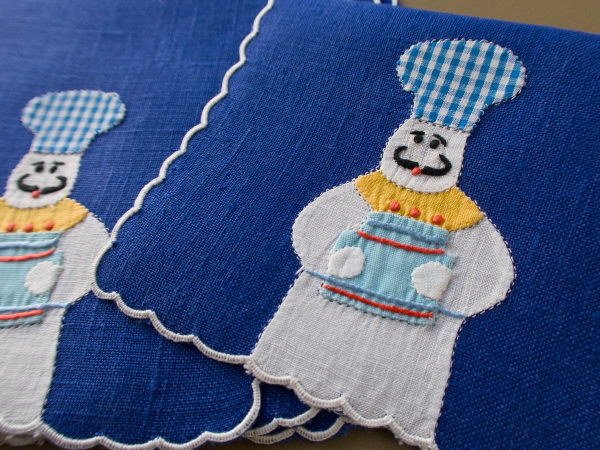 Close view of vintage Madeira cocktail napkin with appliqué baker in gingham cap and scalloped edge