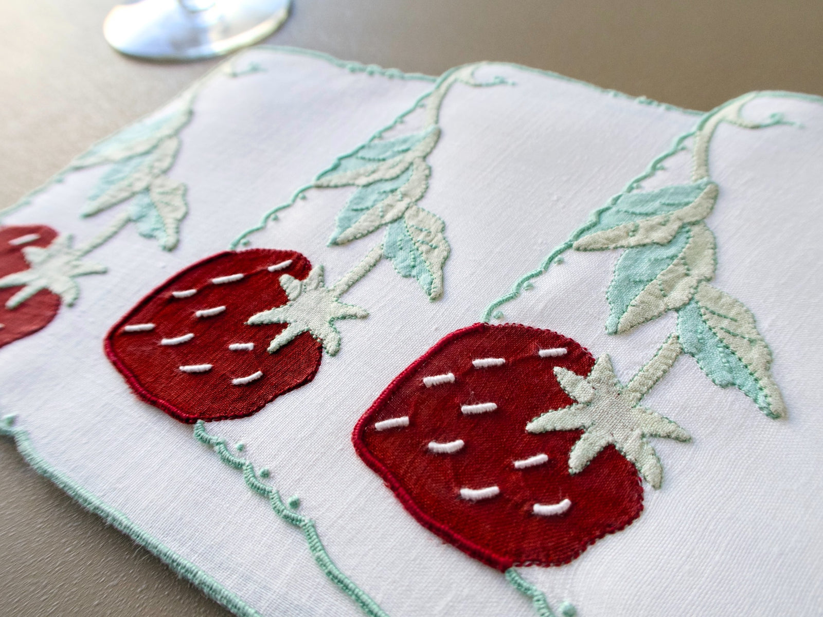 Vintage Madeira cocktail napkin with hand embroidered appliqué strawberries and leafy vines along the edge