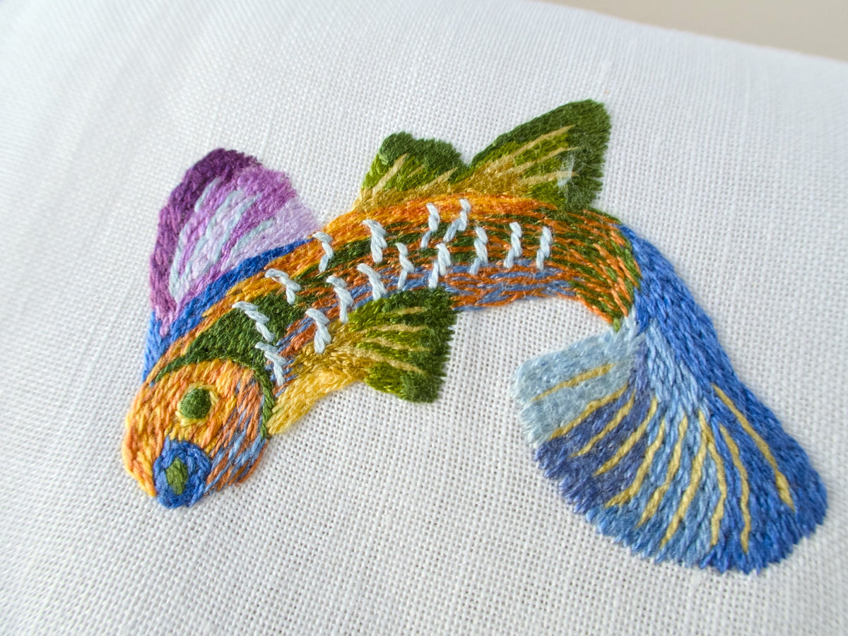 Close view of colorful tropical fish hand embroidery on vintage Léron linen cocktail napkin with celadon border detail.