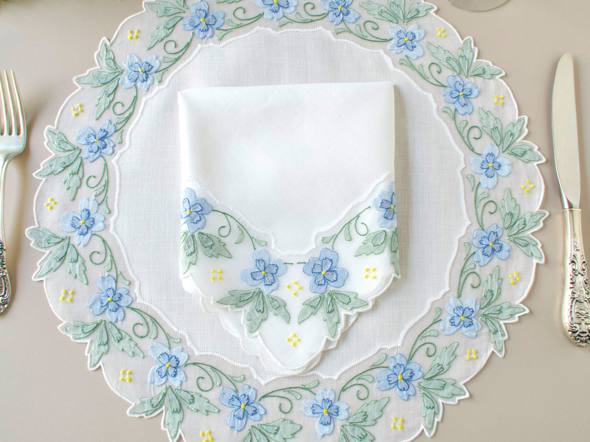 Vintage Madeira round placemat and matching linen napkin, hand embroidered with blue and green shadow work flowers and leaves, granitos, and vining on scalloped organdy border