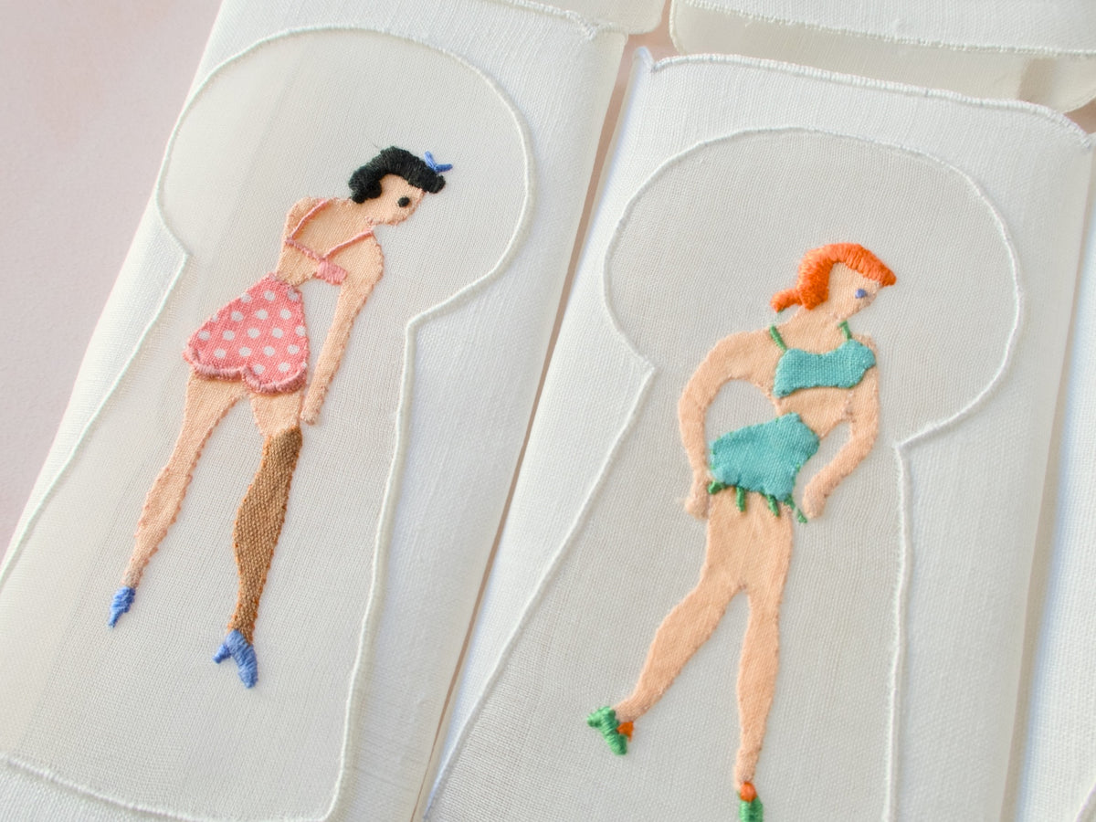 Detail of keyhole embroidery showing woman in green lingerie, vintage Madeira linen cocktail napkin.