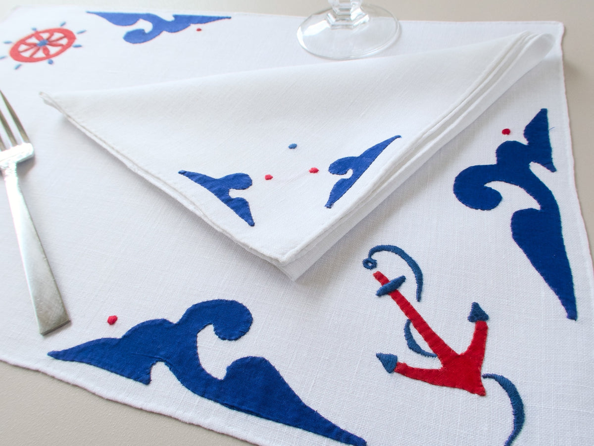 Vintage Italian hand embroidered nautical placemat set for 8, navy and red anchors, ship’s wheels and rolling waves on white linen, with table runner.