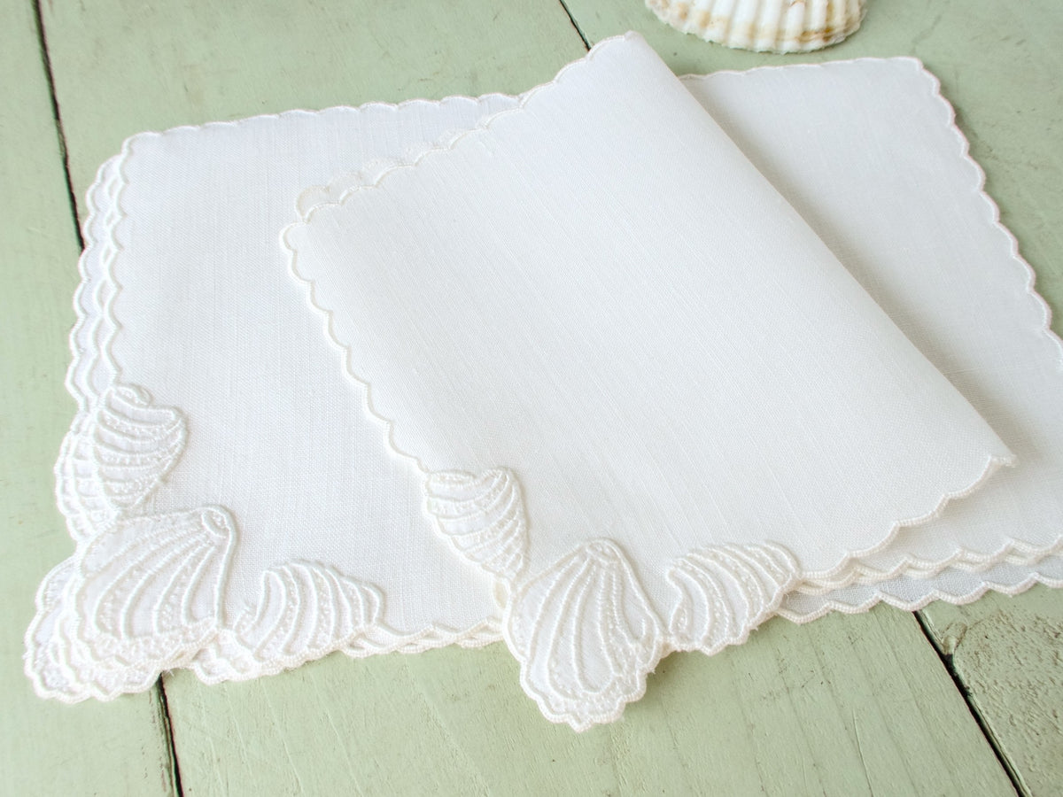 Vintage white Madeira embroidered cocktail napkins fanned and stacked, showing scalloped edges and shell motif.​​​​​​​​​​​​​​​​