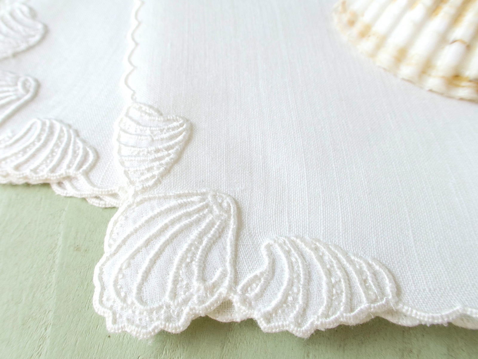 Close view of raised white shell embroidery on vintage Madeira Irish linen cocktail napkin, dense dimensional handwork.