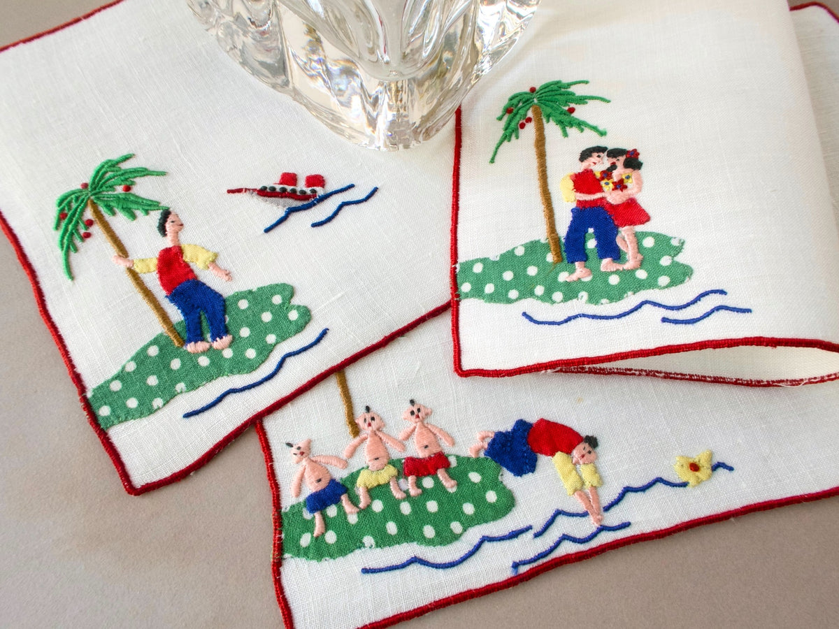 Vintage Madeira cocktail napkins showing playful tropical island scenes — a man stranded on an island, a couple embracing, and man swimming away from shore.