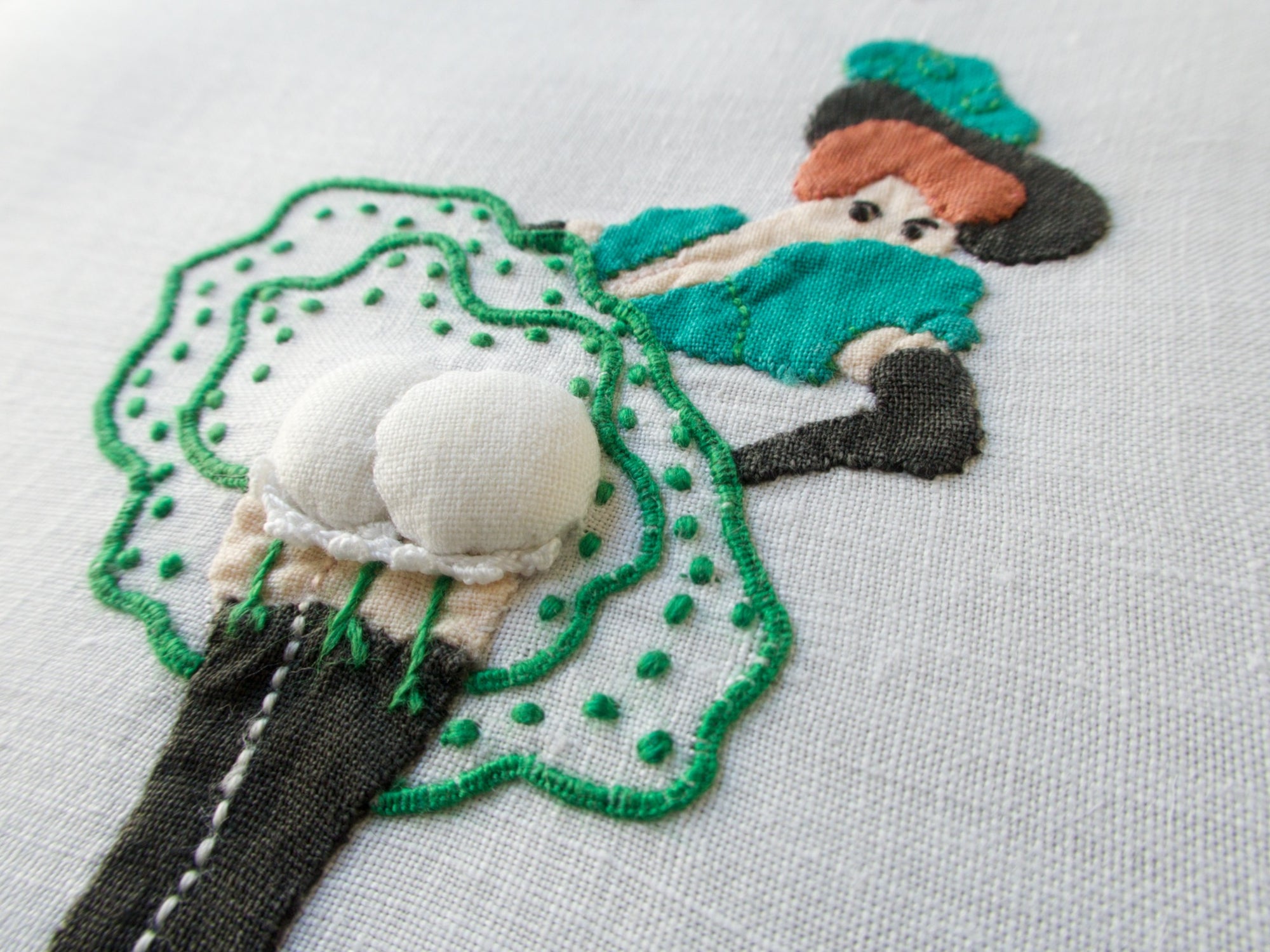 Close-up of vintage Madeira linen cocktail napkins by Paragon featuring playful hand-embroidered ladies with dimensional appliqué and bright colors