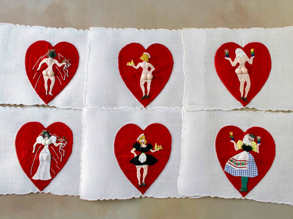 Set of six vintage Madeira cocktail napkins with red heart appliqués and playful embroidered ladies.