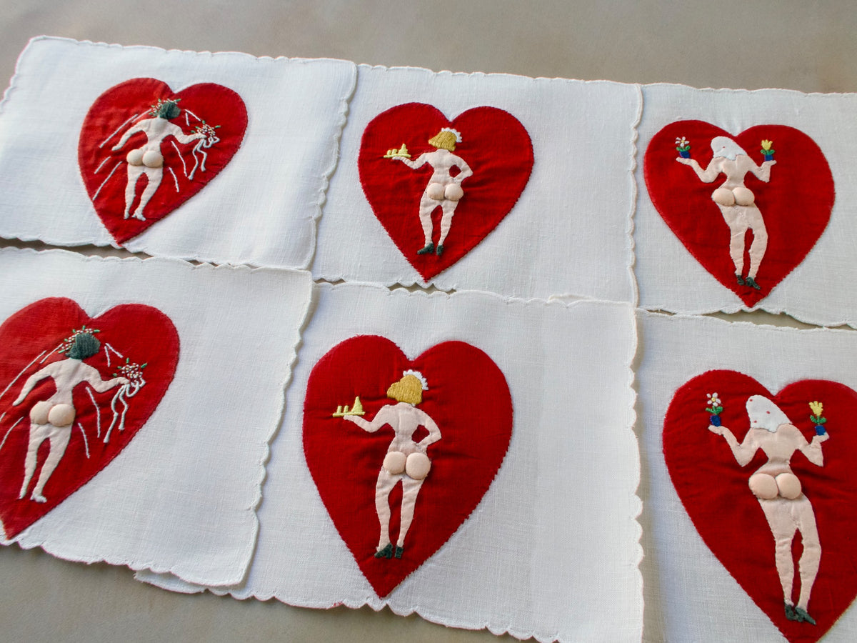 Vintage Madeira cocktail napkins featuring red hearts with naughty figures on white linen