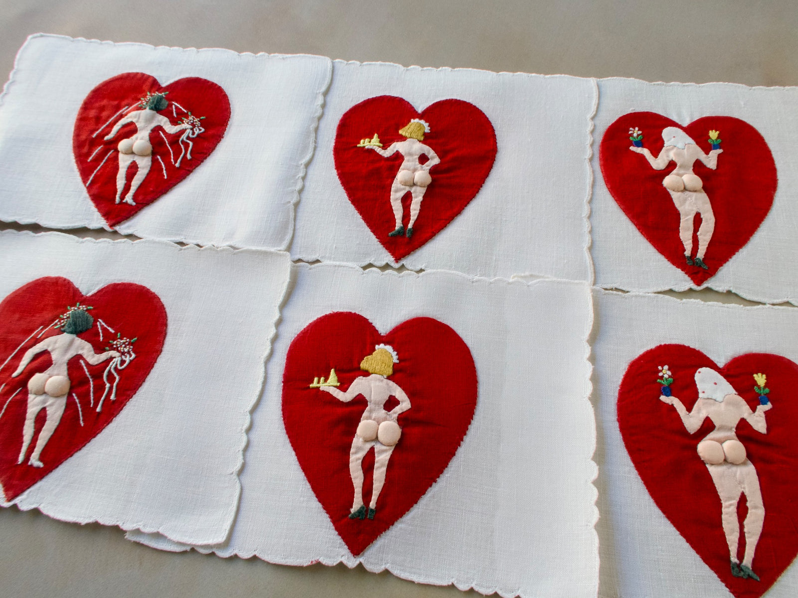Vintage Madeira cocktail napkins featuring red hearts with naughty figures on white linen