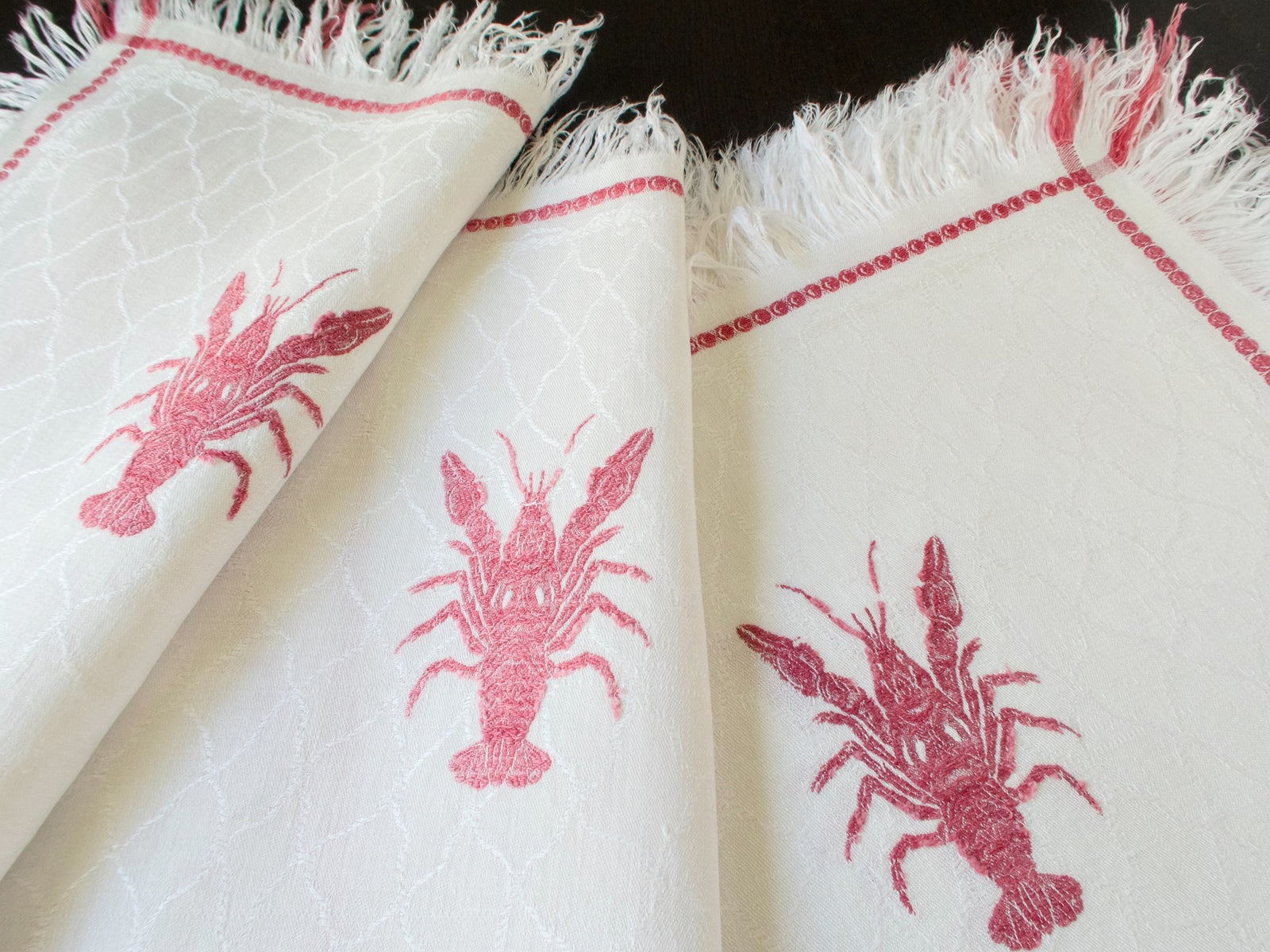 Three antique French lobster damask napkins fanned showing different crustacean motifs