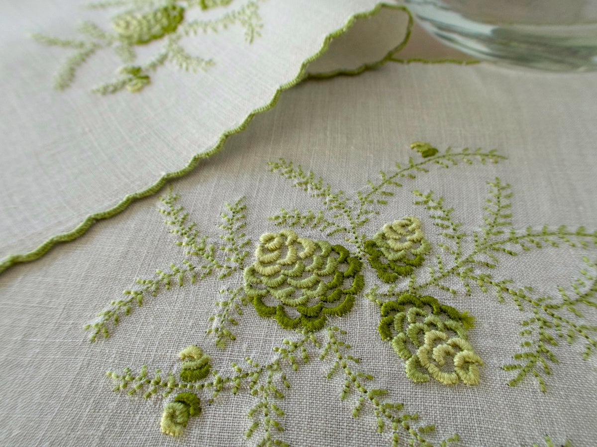Embroidered green pinecone motif on linen cocktail napkin with scalloped edge, hand embroidered in Madeira.