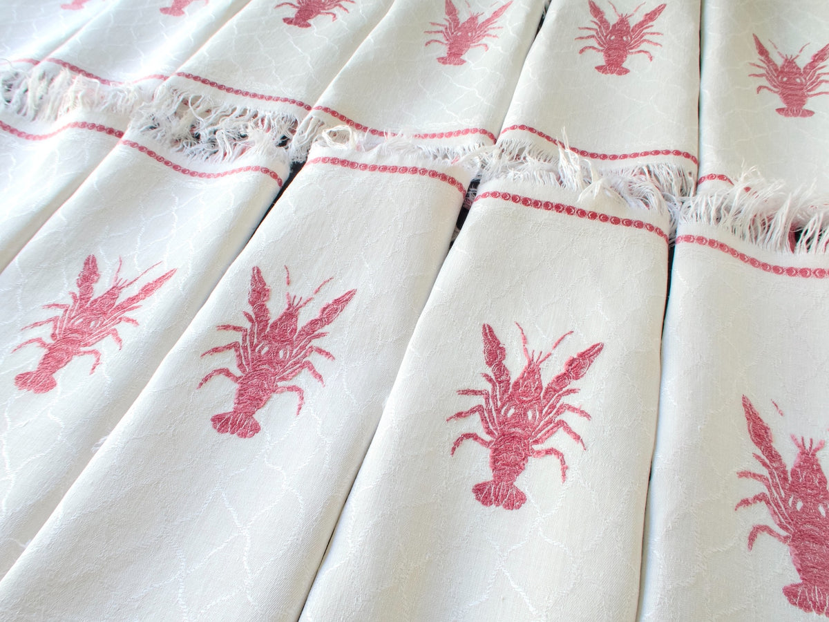 Folded antique French lobster damask napkins lined up showing fishnet damask weave and fringe