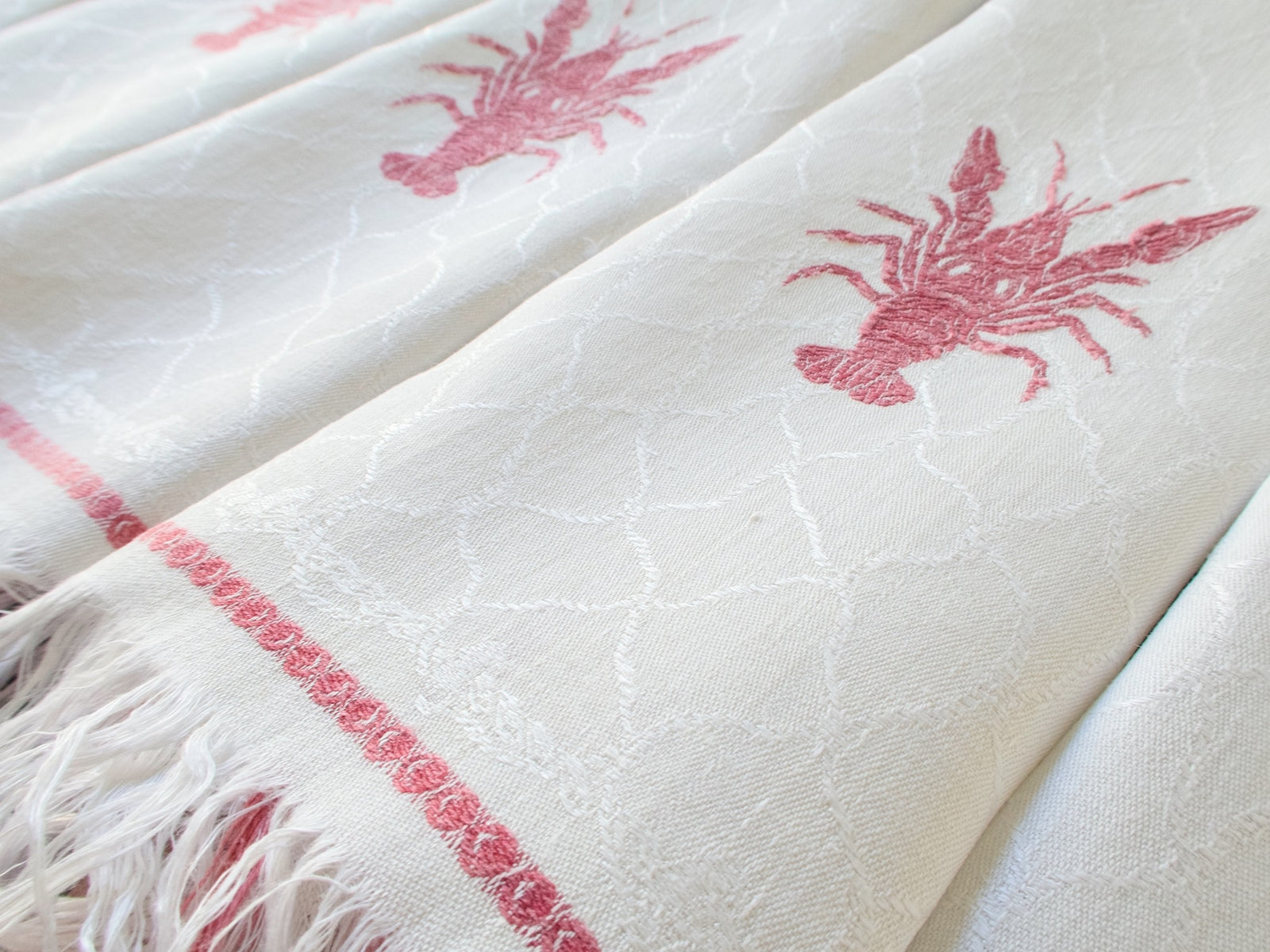 Close-up of red lobster on antique French damask napkin showing fishnet and rope border detail weave pattern