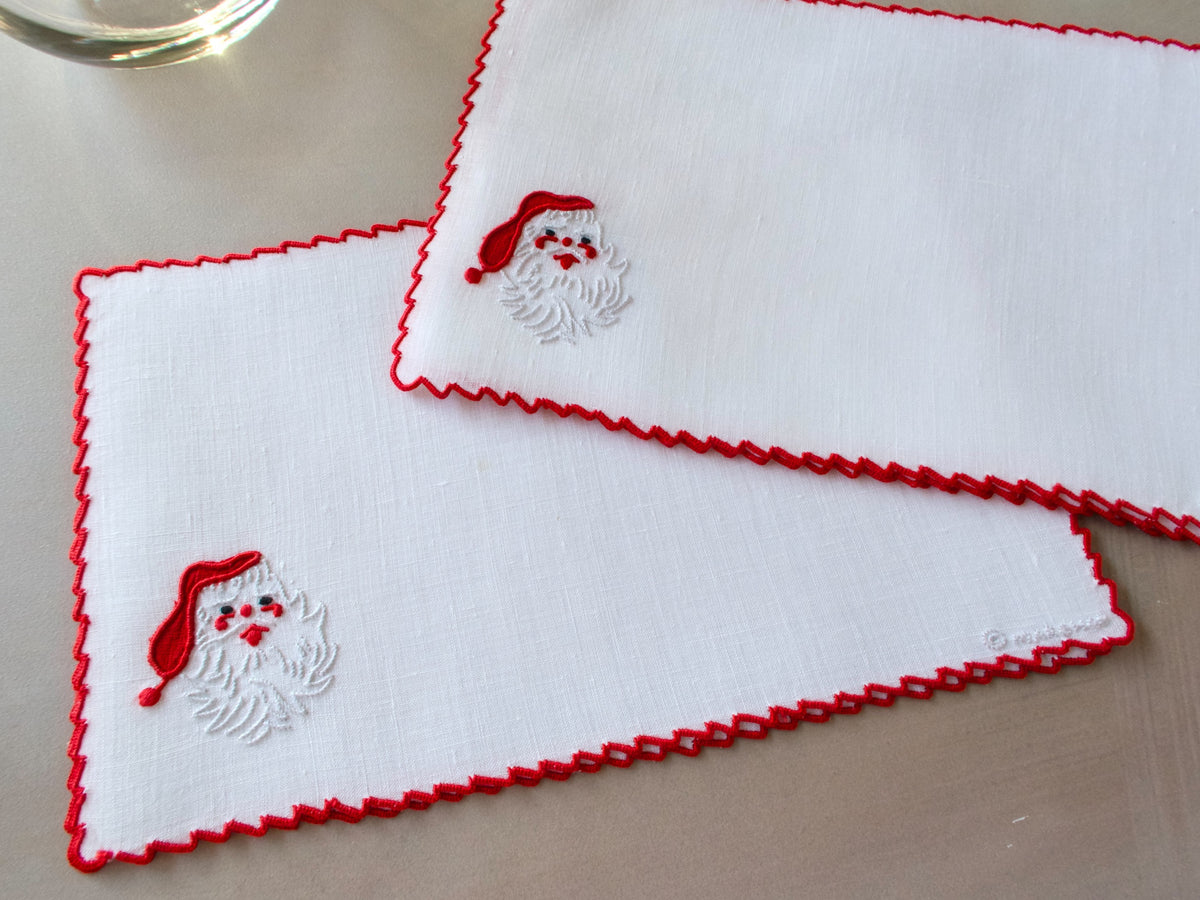 Embroidered Santa face with red hat and textured white beard on vintage Marghab Madeira cocktail napkin, scalloped edge.