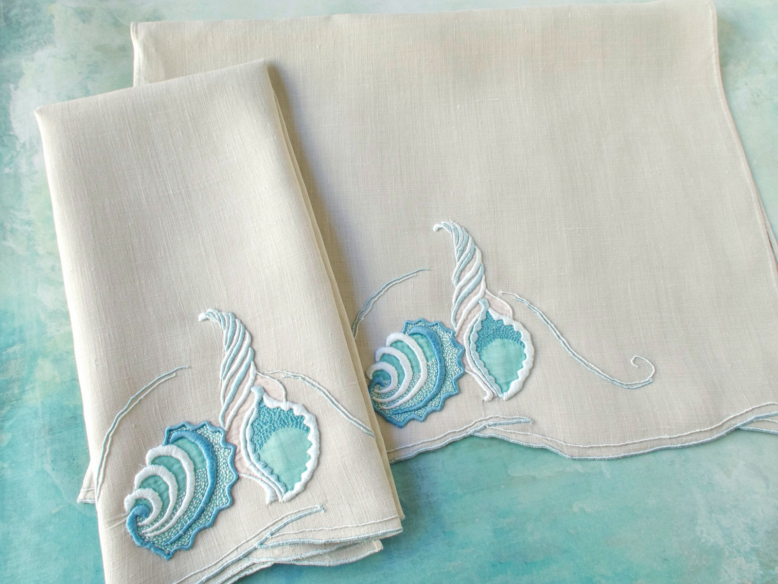 Vintage Marghab “Concha” guest towels folded and stacked, showing blue shell embroidery on fine Irish linen.​​​​​​​​​​​​​​​​