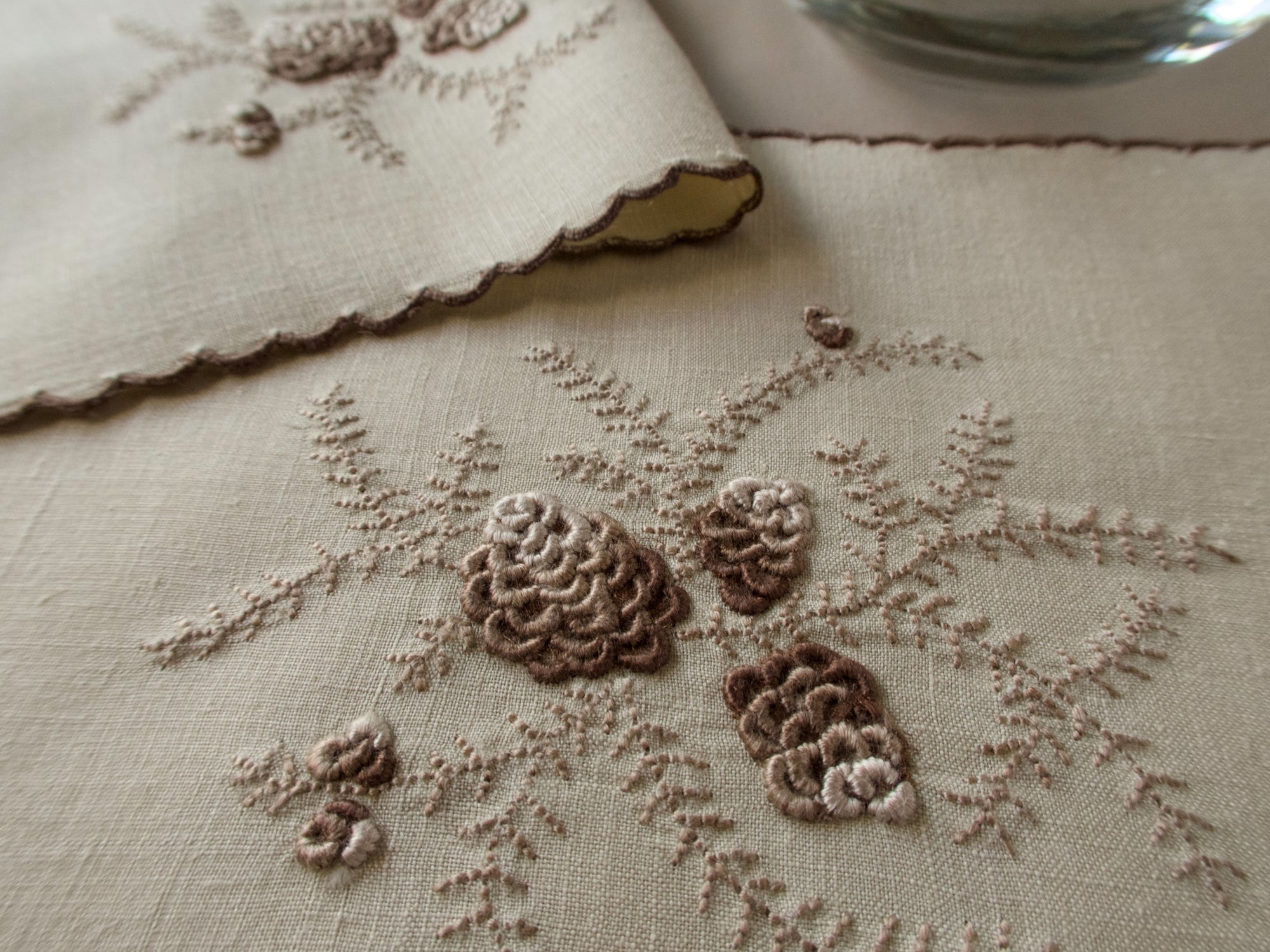 Close shot of Marghab's "Pines Cones" pattern, embroidery on linen cocktail napkin, Madeira handwork.