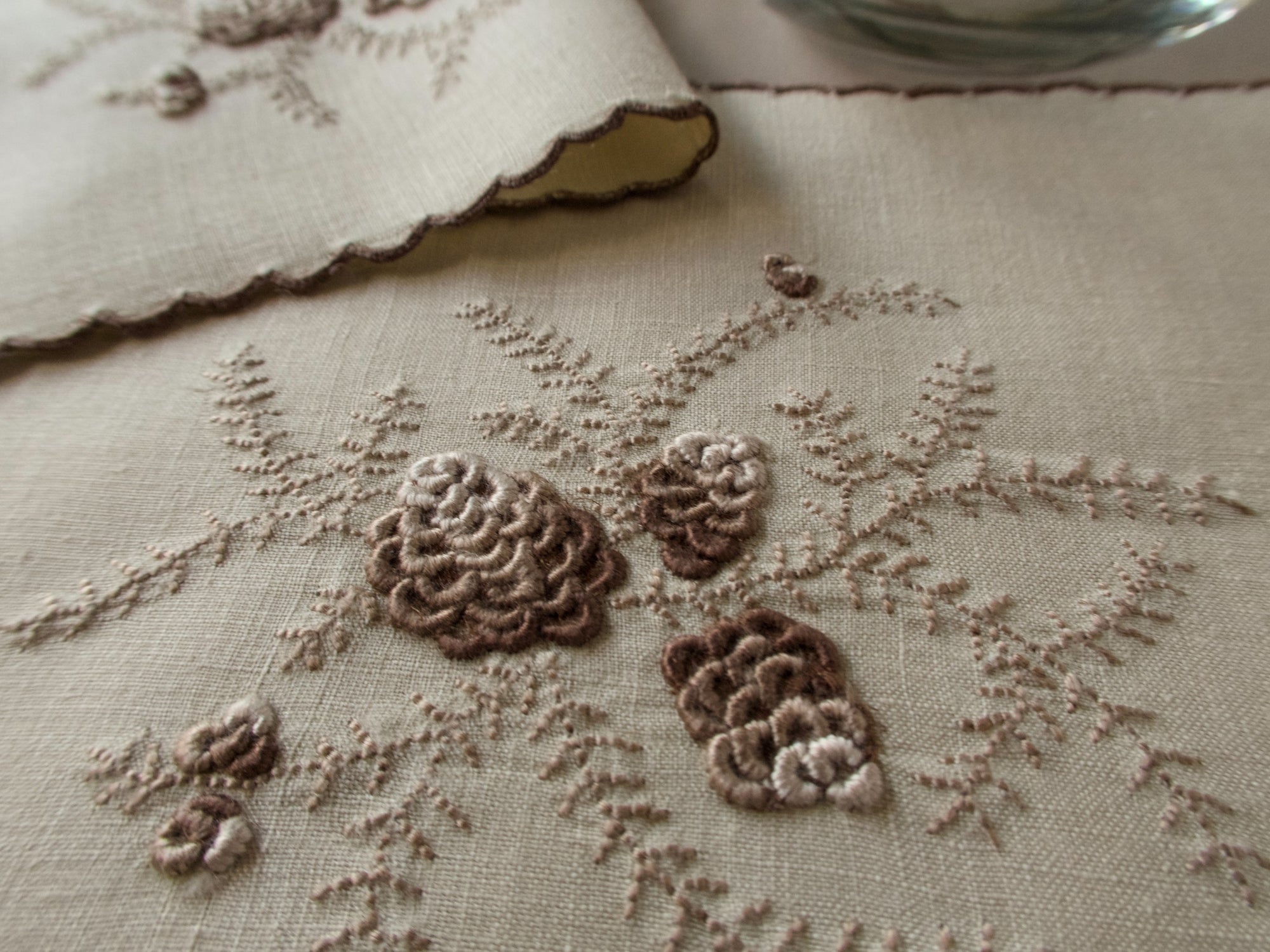 Close-up of raised brown pinecone embroidery on linen cocktail napkin, Marghab pattern, Madeira handwork.