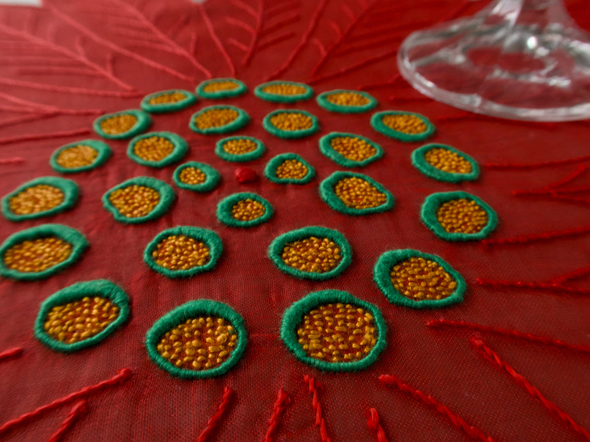 Close-up of embroidered center on red poinsettia-shaped organdy placemat.