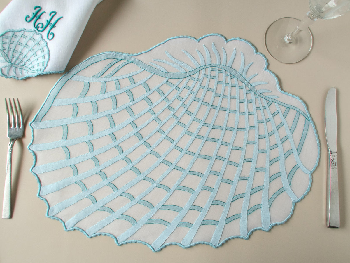 Vintage Léron organdy shell-shaped placemat with monogrammed linen napkin, fork and knife, beige background — Madeira shadow work embroidery