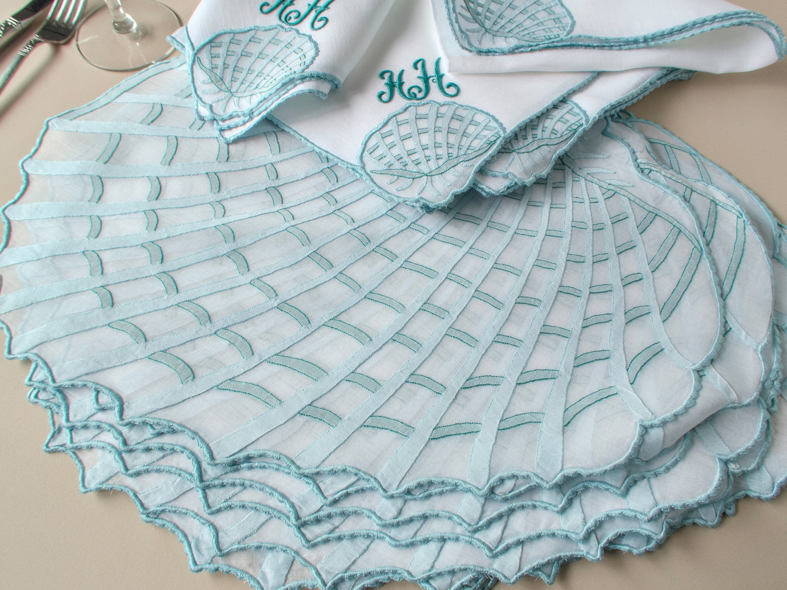 Stacked vintage Léron organdy placemats with draped monogrammed napkin, showing scale and caseado bastido edge detail​​​​​​​​​​​​​​​​
