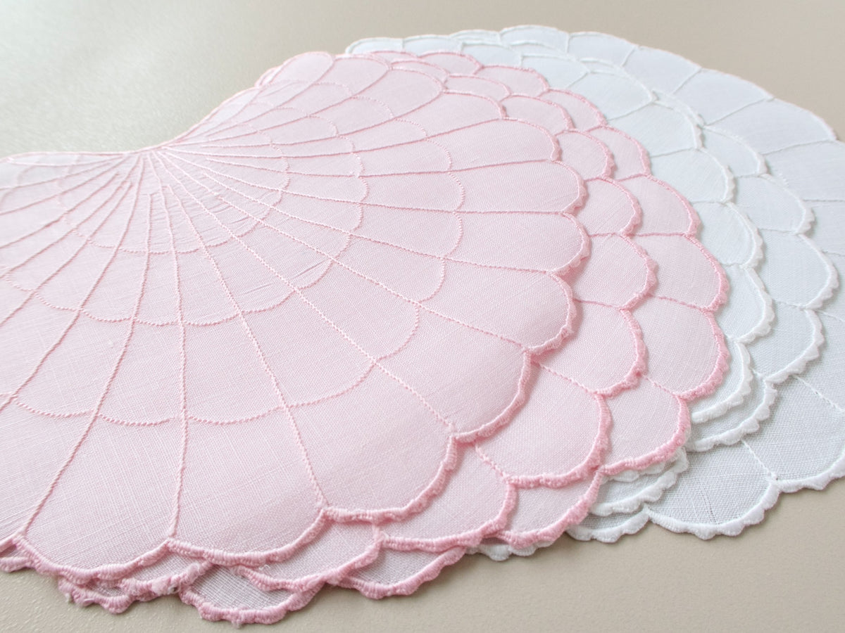 Pink and white scallop shell-shaped Madeira cocktail napkins, cut linen, with radiating embroidered lines and scalloped edges.