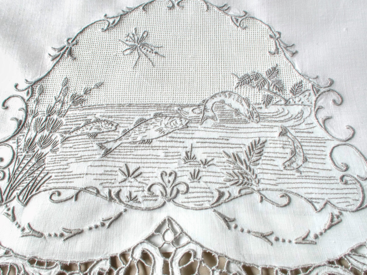 Antique Italian hand embroidered guest towel, fish swimming among reeds and water plants beneath open mesh sky with dragonfly, scrolling floral border.